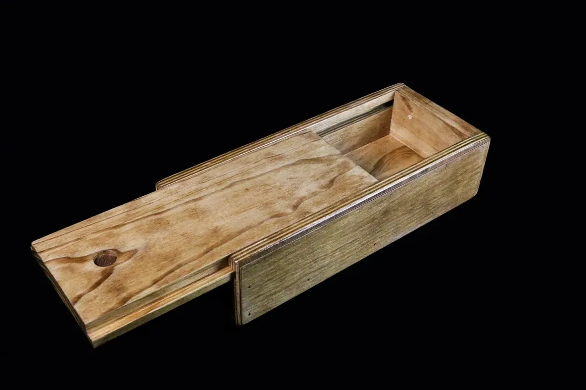 A wooden box with a sliding lid on it.