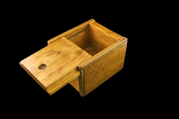 A wooden box with a sliding lid on top of it.