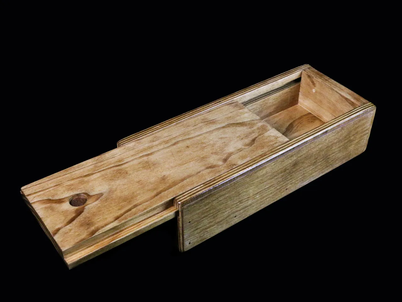 A wooden box with a sliding lid on top of it.