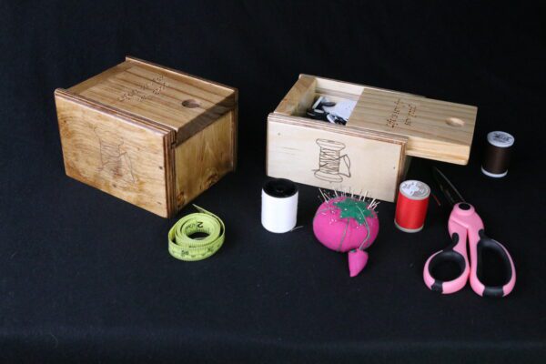 A table with two wooden boxes and some thread spools.