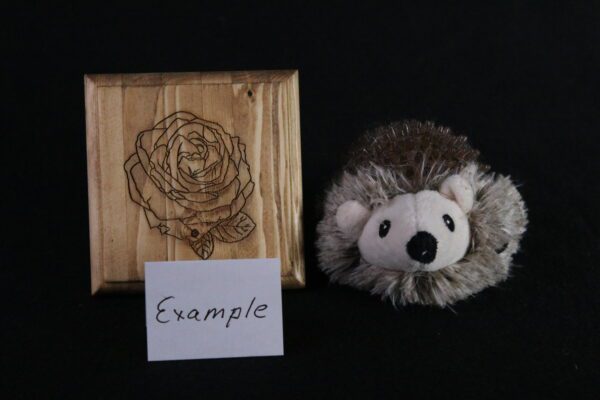 A stuffed animal and wooden plaque with an image of a rose.