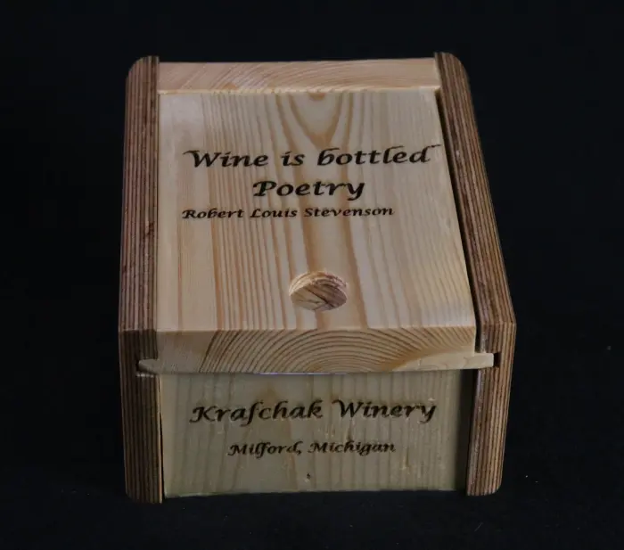 A wooden box with the words " wine is bottled poetry " written on it.