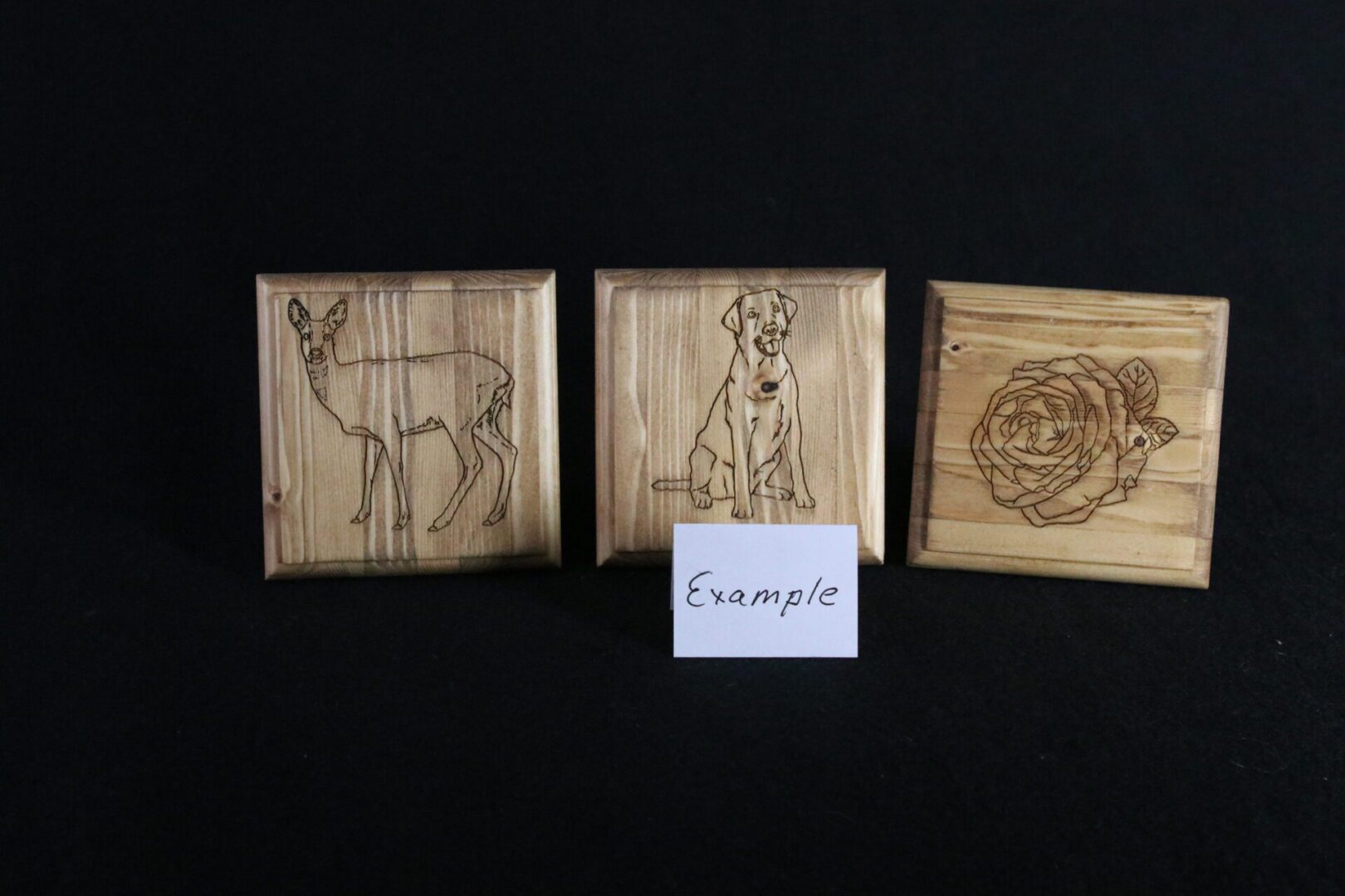 A group of three wooden pictures with different designs.